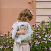 A beige floral-patterned Olli Ella Doll Carrier with padded straps designed for carrying dolls.